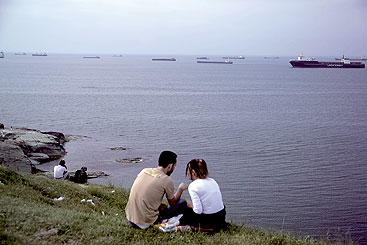 a group of people sitting next to a body of water