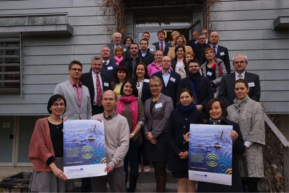 a large group of people standing on a porch together holding up signs that show the JOINTISZA Project