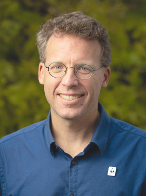 a man wearing glasses and smiling at the camera