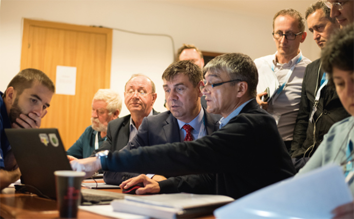 a group of people sitting at a table using a laptop