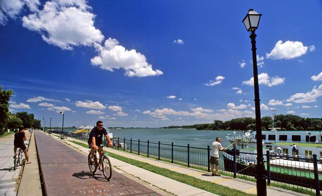 a person riding a bicycle on the side of a fence next to a river