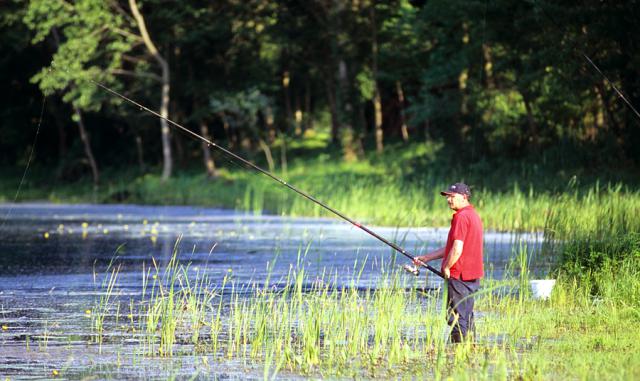 a man standing and angling at a body of water 