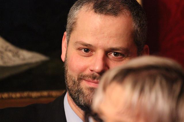 a man wearing a suit and tie smiling and looking at the camera