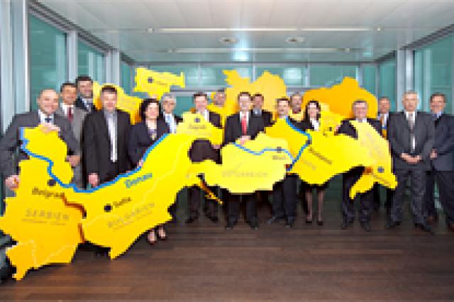 A group of people holding up country shapes posing for a picture 